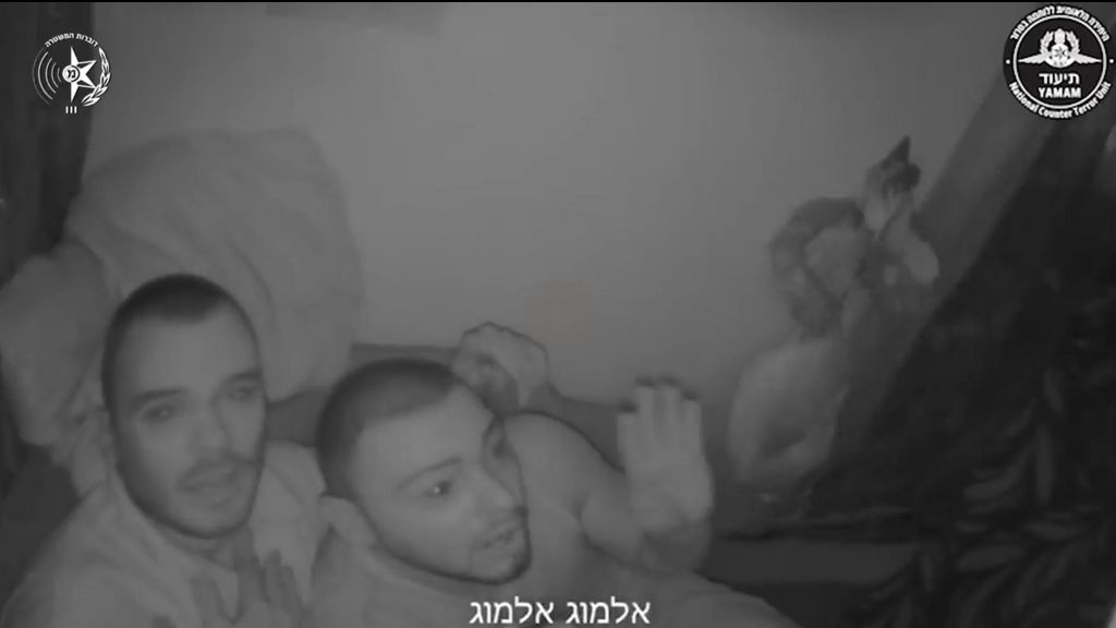 Still from Israel Police bodycam footage shows Andrei Kozlov (L) and looking in distress sat on sofa