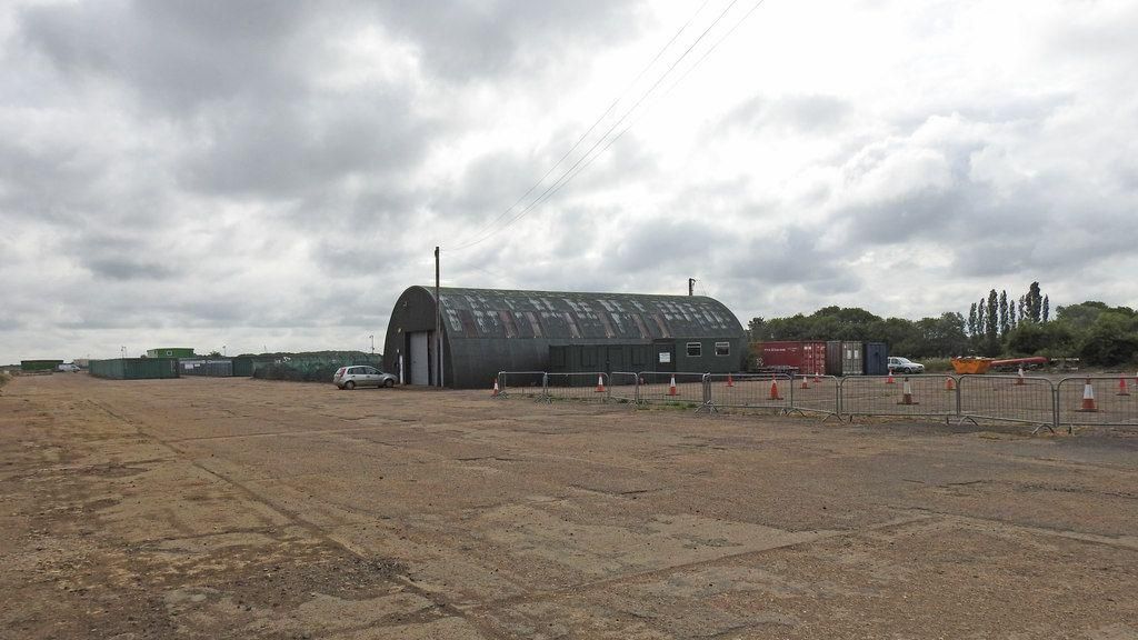 The runway at Bourn Airfield with silver barriers and a hangar