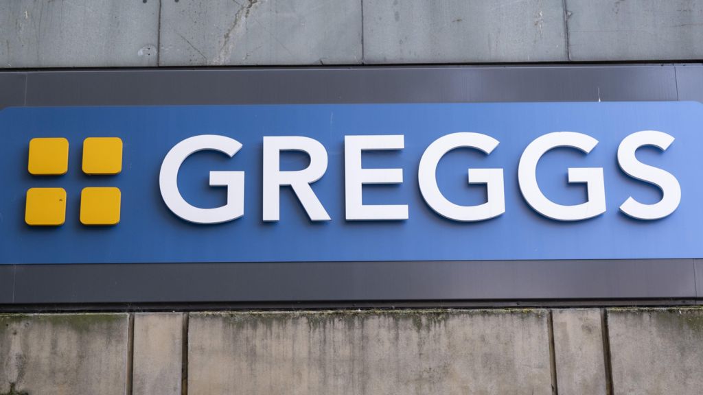 The 'Greggs' logo, which is the company's name in white against a blue background, with four yellow squares to the side.