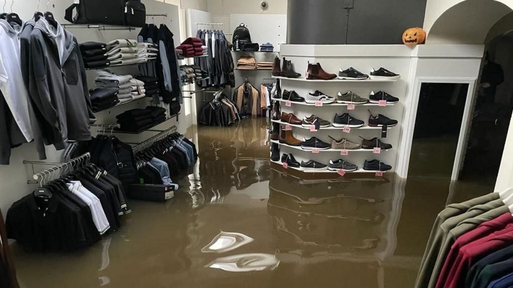 Racks of clothes and shelves of shoes covered in floodwater