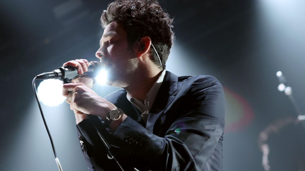 Matty Healy of The 1975 singing into a microphone on stage