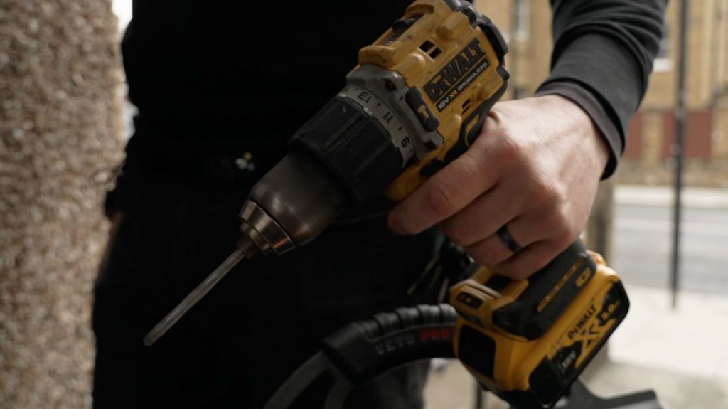A man's hand is seen holding a large cordless drill