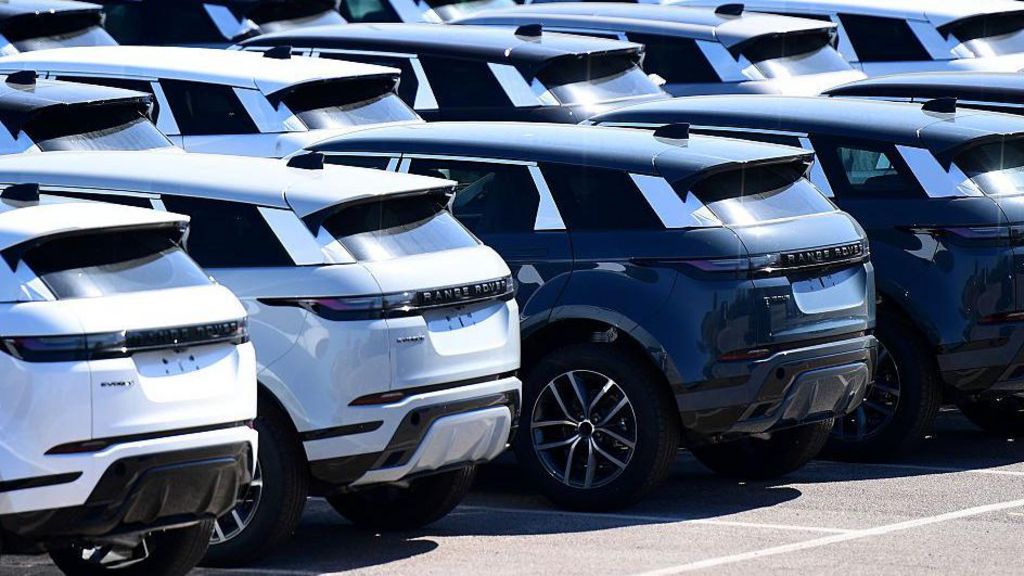 A row of brand new Range Rover cars, some white and some black, standing outside the Jaguar Land Rover factory in Halewood, England