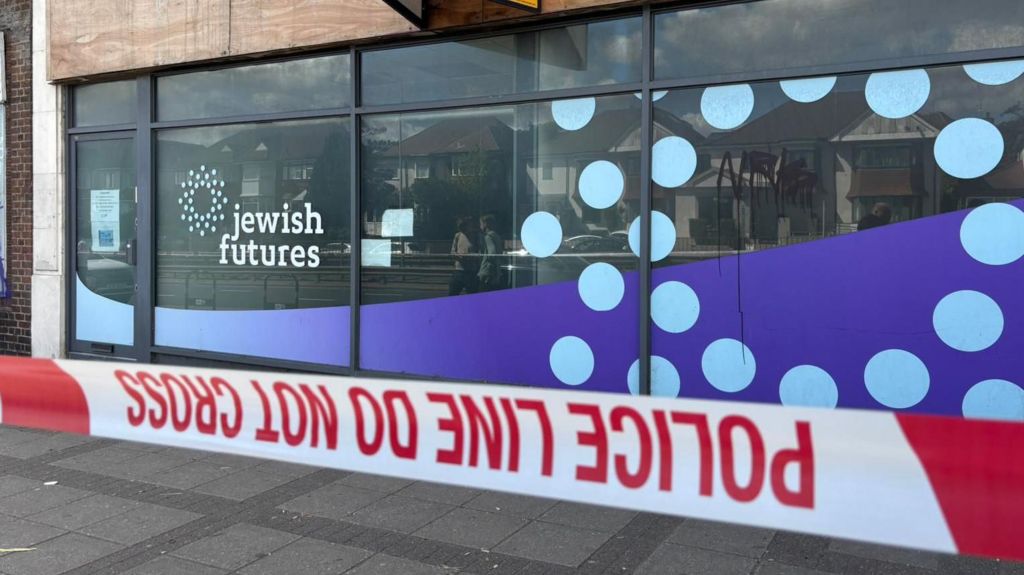 Exterior of a building displaying Jewish Futures signage, with police cordon tape across the pavement in the foreground