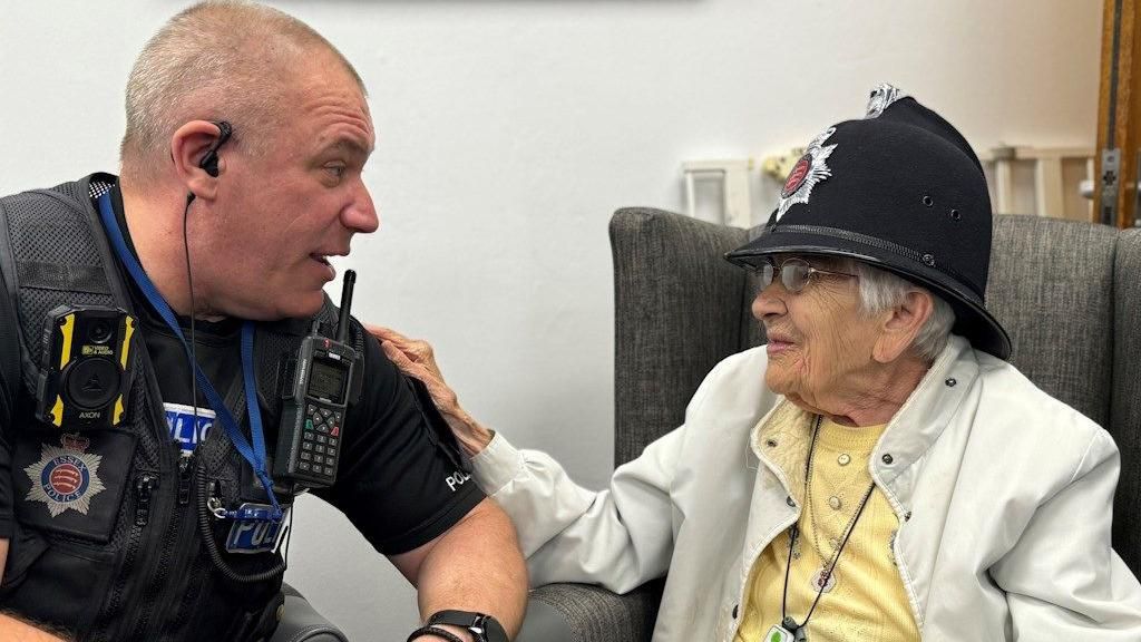 Police officer Neil Brand with Gwen Lewis wearing a police helmet