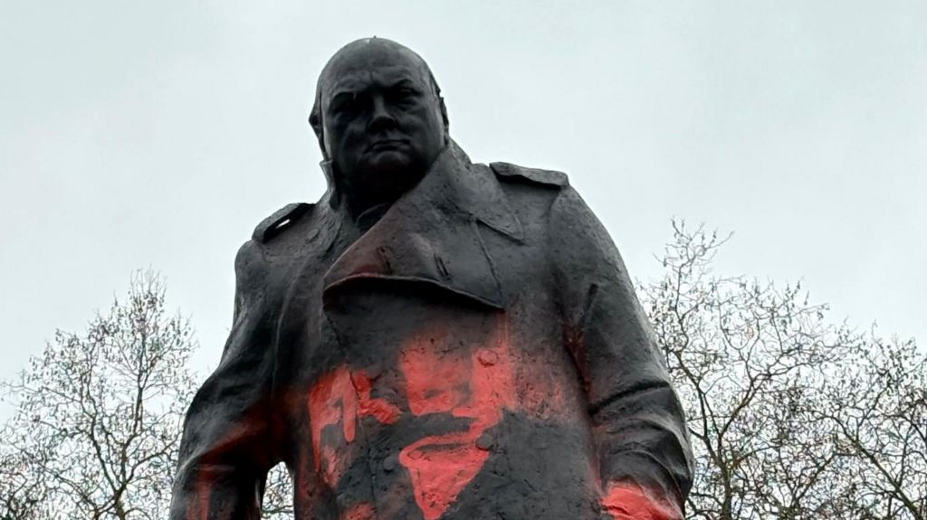 Black statue of Winston Churchill with red graffiti 