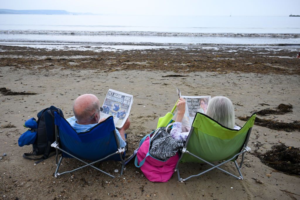 A couple sit next to seaweed on Weymouth beach