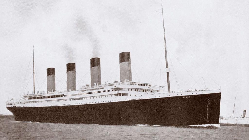 A black and white photo of the Titanic, a large cruise linger with a black hull, two masts and four chimneys.