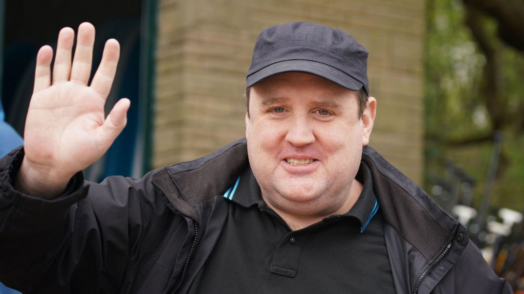 Peter Kay wears a cap and looks towards the camera