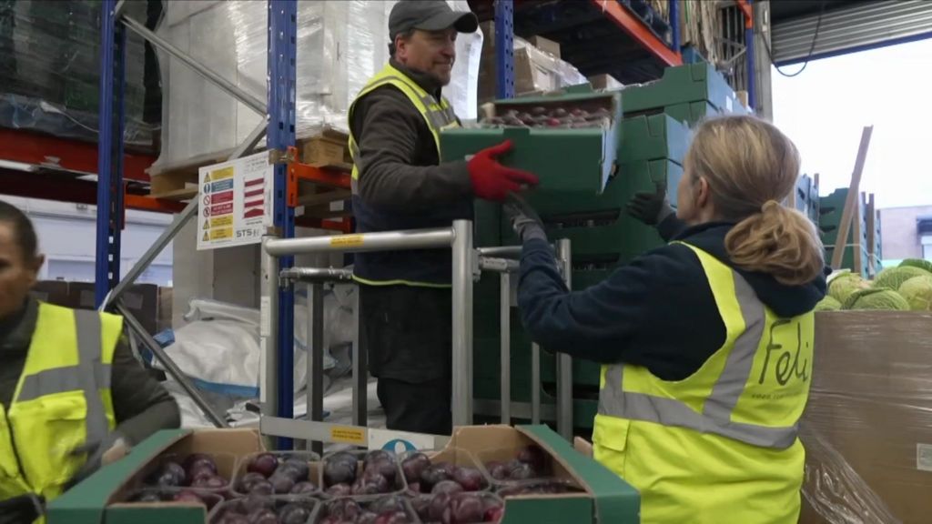 People in high-vis jackets moving crates of food 