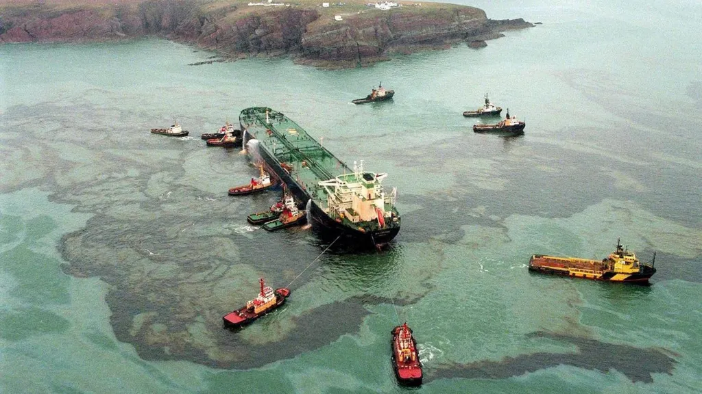 A striking photo from the air of the Sea Empress tanker, surrounded by tugboats and vast swathes of oil polluting the sea around it.