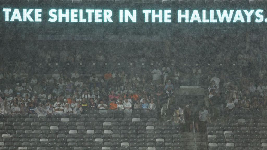 Fans take shelter from the rain during the friendly between Barcelona and Real Madrid