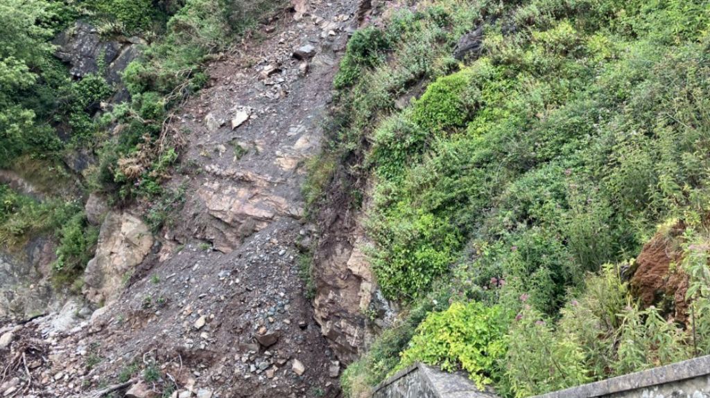 A landslide with mounds of rocks gathered at the bottom on the beach