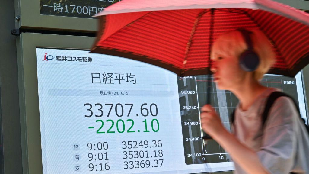 A pedestrian walks past a display board showing the morning numbers on the Tokyo Stock Exchange.