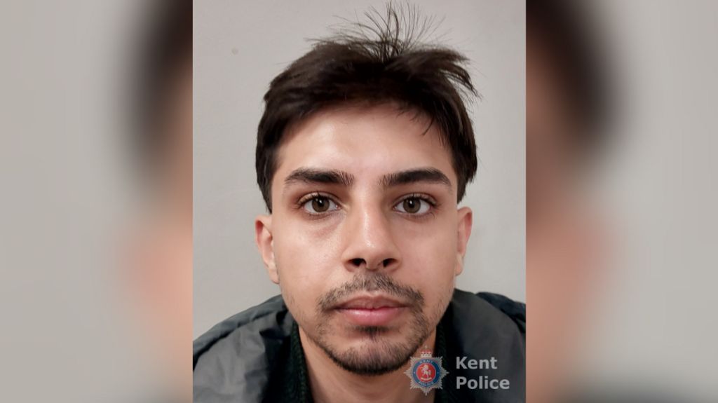 A mugshot of a man with brown hair and dark stubble.