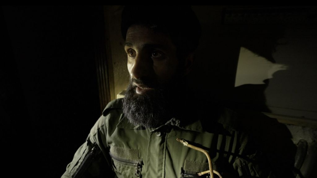 A photo of Abu Jarrah, face lit alone in the dark.