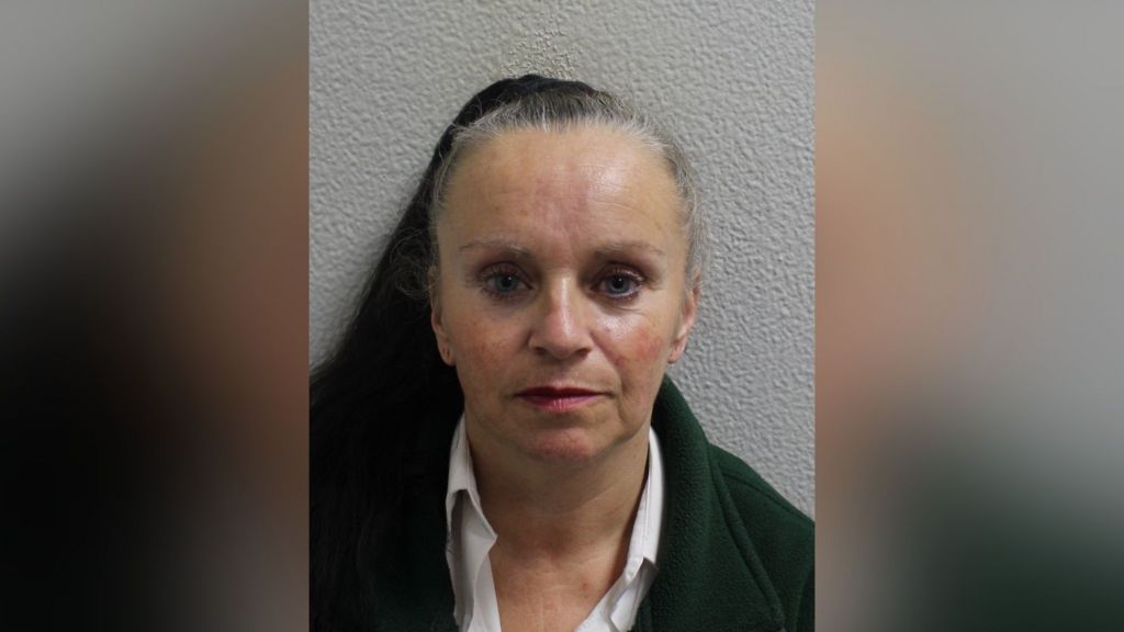 Custody image of Tina Smith, wearing a dark jacket and white shirt, photographed against a plain wall.