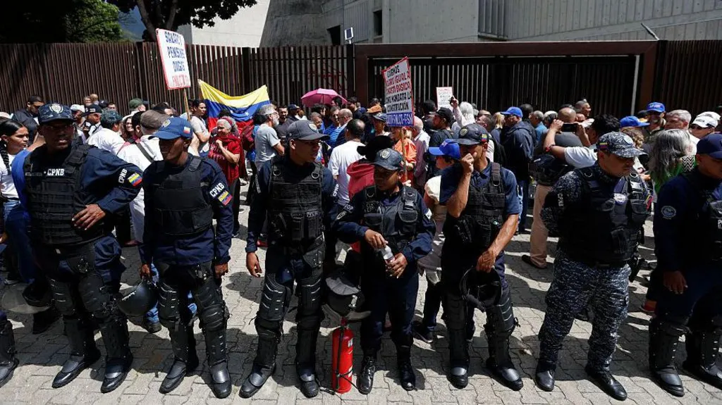 Venezuelan policemen stand in front of a protest in Caracas over low wages