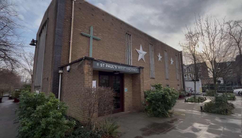 Brick church with silver stars on the outside surrounded by shrubbery.