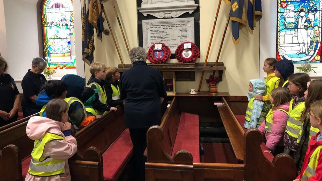 Children watch as a wreath is laid in a Manx church to mark D-Day