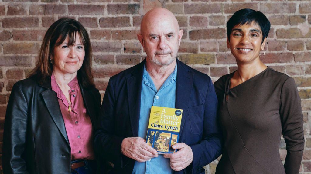 Daisy Goodwin, Nick Hornby and Reeta Chakrabarti standing and posing together, with Hornby holding a copy of Claire Lynch's book