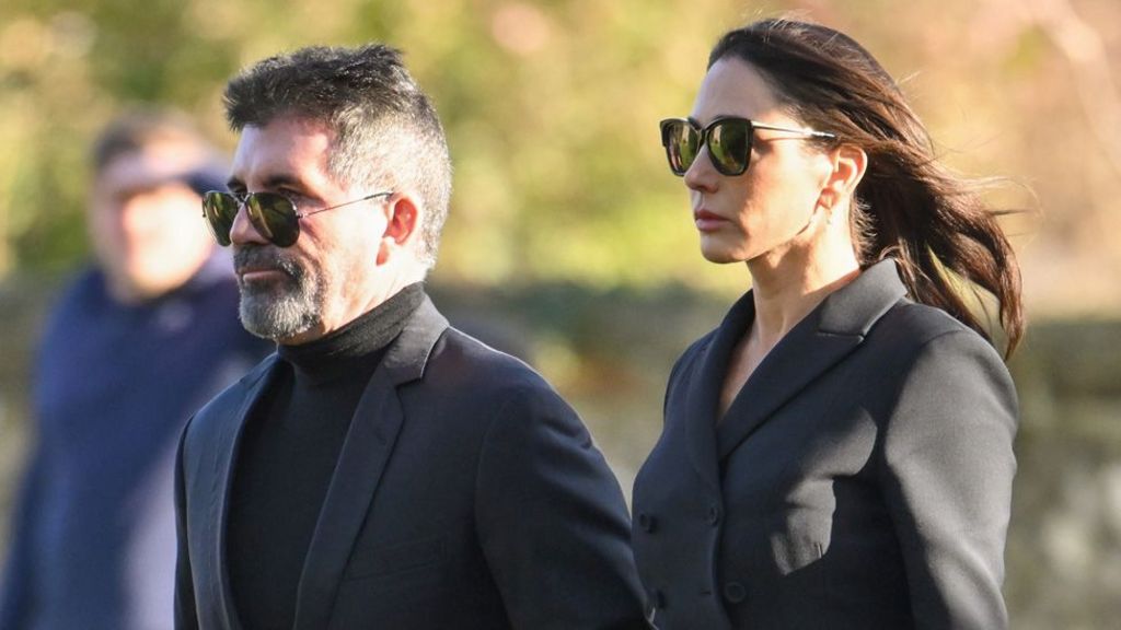 Simon Cowell and Lauren Silverman walking together in grey suits