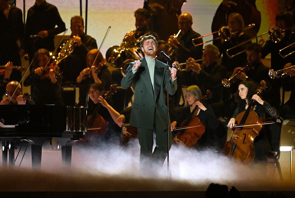 Alex Warren performs on stage in an all green suit.