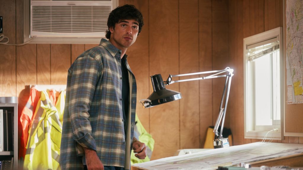 Jacob Elordi as Nate in a checked shirt standing next to a drawing on an architect's desk with an angle-poise lamp in a still from Euphoria