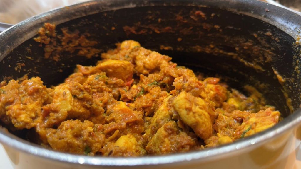 Chicken curry shows pieces of meat with spices in a curry sauce