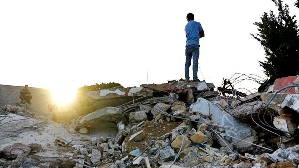 A man stands on top of rubble from a building destroyed in an Israeli air strike in Saksakiyeh, southern Lebanon, which killed nine members of one family