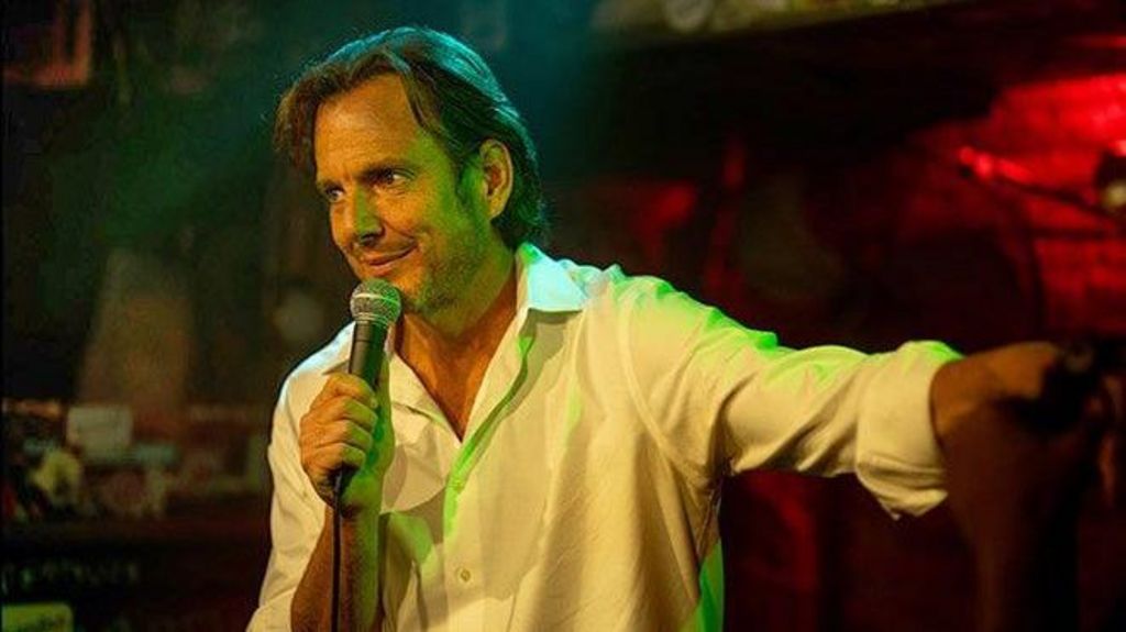 Will Arnett performing on stage holding a microphone in Is This Thing On?