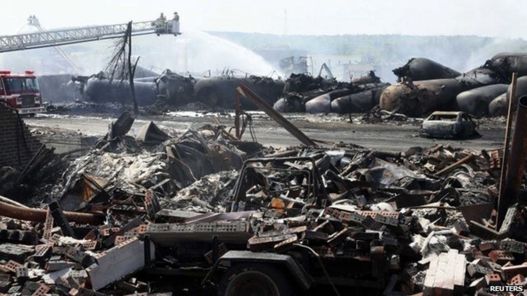 Canadian Prime Minister Stephen Harper visits Lac-Megantic as firefighters continue to spray derailed tanker cars, 7 July 2013