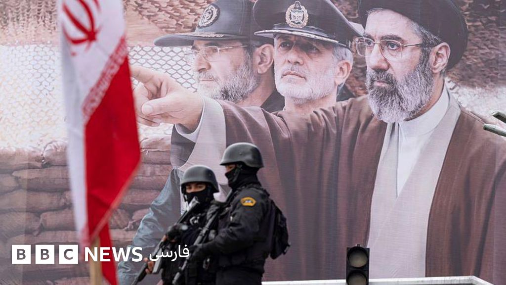 تصویری از بنر تبلیغاتی مجتبی خامنهای در حالی که دو مامور امنیتی سیاهپوش با اسلحه مقابلش ایستادهاند