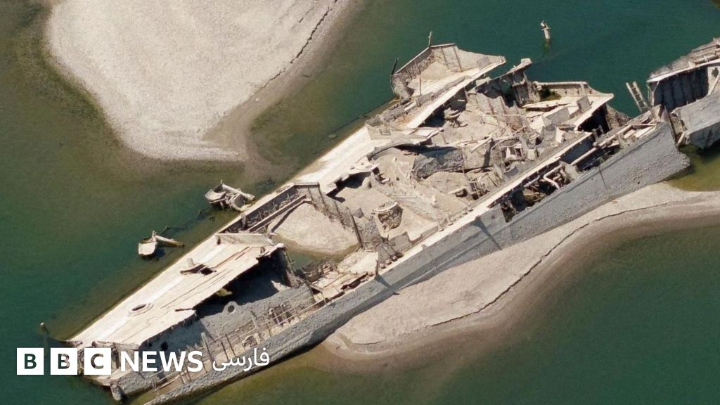 A large shipwreck is visible next to a white sandbank in green waters.