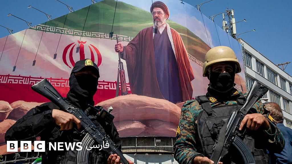 اعضای نیروهای امنیتی ایران در مراسم بزرگداشت چهلمین روزی که حملات مشترک آمریکا و اسرائیل، علی خامنهای، را به قتل رساند، زیر تصویر بزرگی از مجتبی خامنهای، رهبر جدید ایران، نگهبانی میدهند.