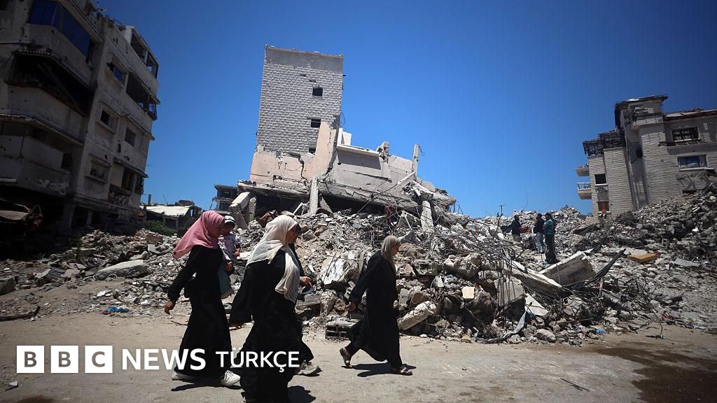 Photo: BBC Üç kadın molozların önünden yürüyor
