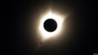 A jet plane flies by the total solar eclipse