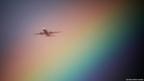An aeroplane flies near a rainbow