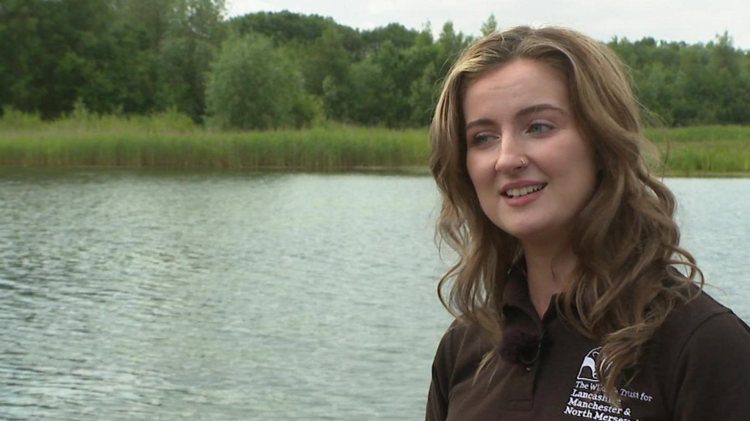 Lydia German wearing a Lancashire Wildlife Trust standing by a river
