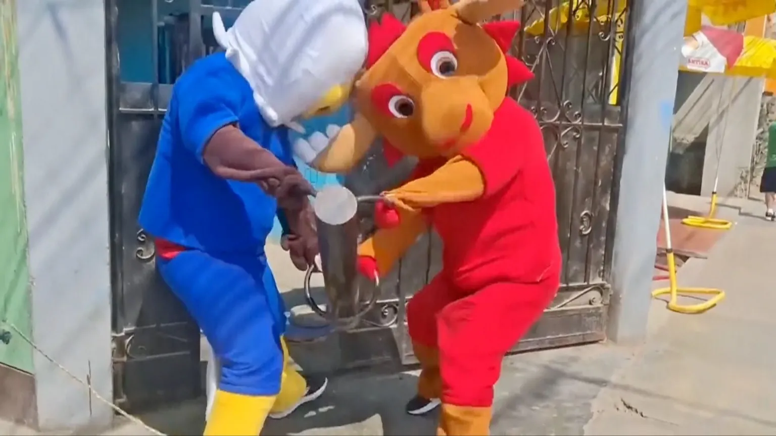 Two World Cup mascots breaking into an iron gate with a metal pole.