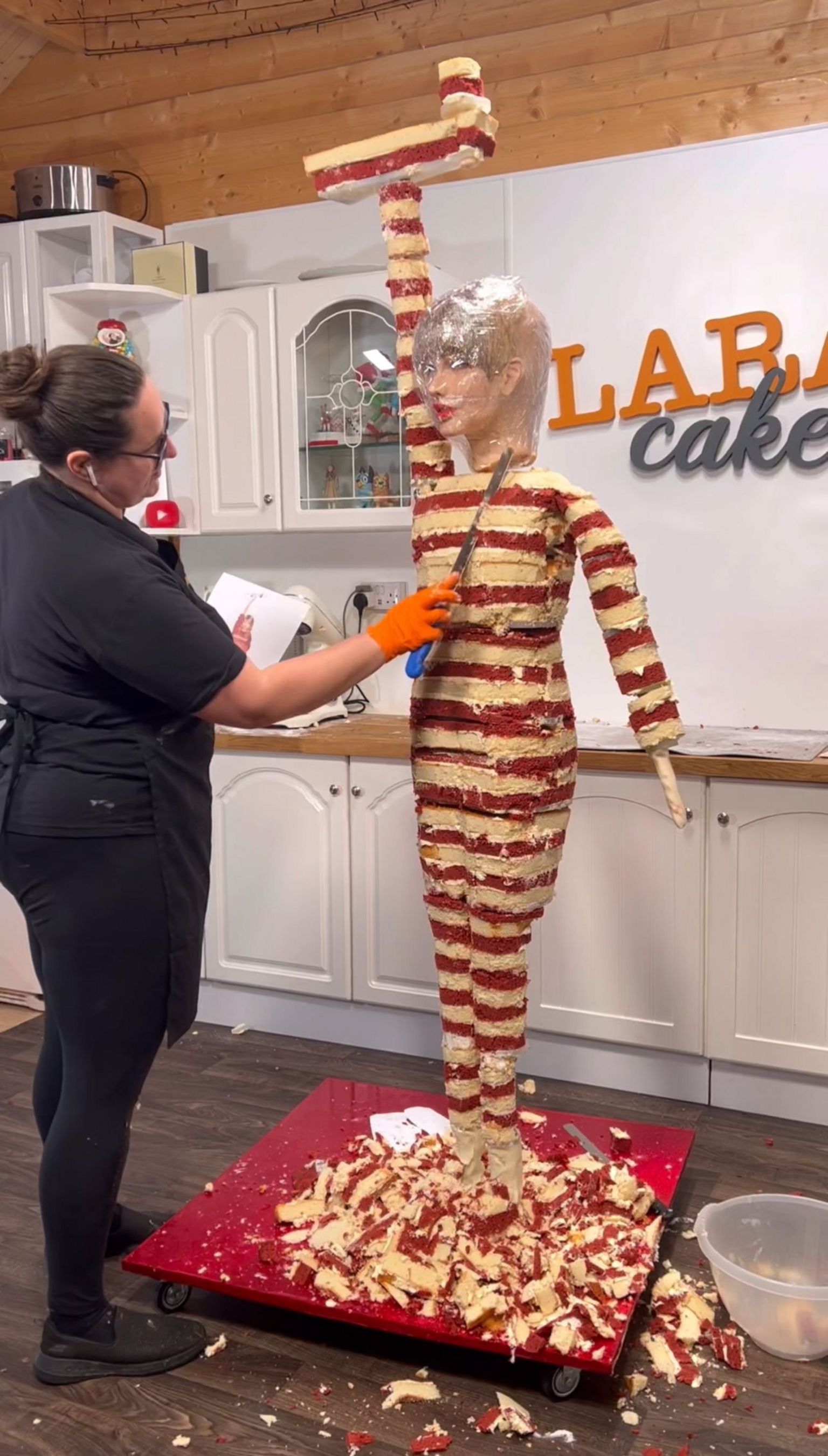 Lara Mason making the life-size cake, with the cake layers visible from the neck down