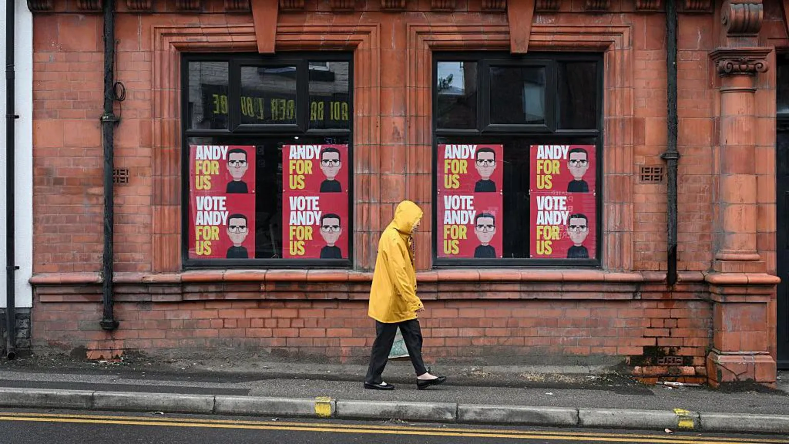 Getty Images A man walking past Andy Burnham signs