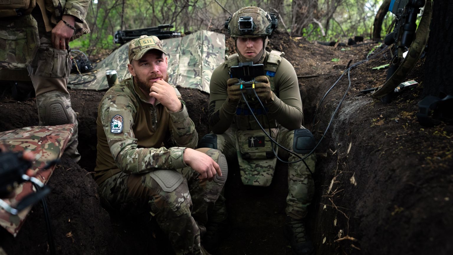 Ukrainian drone operators sit in a trench near Kharkiv