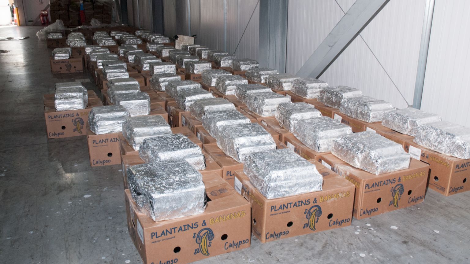 Cardboard banana boxes with silver packages on top lined up in a warehouse