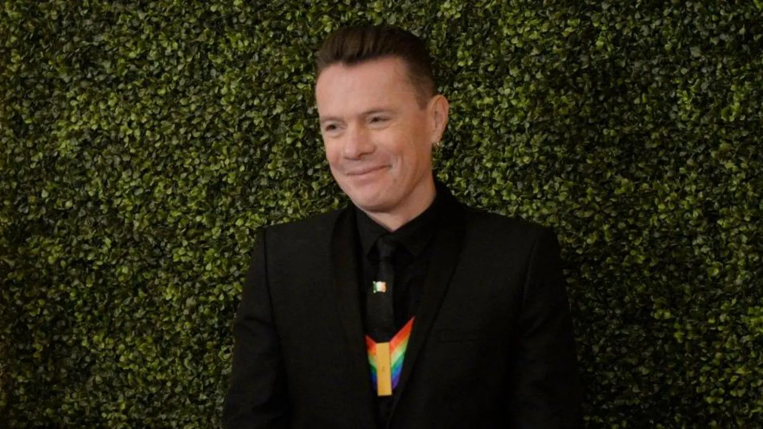 Bloomberg via Getty Images Larry Mullen Junior, a man with fair hair, wearing a dark suit. There is a green hedge in the background.