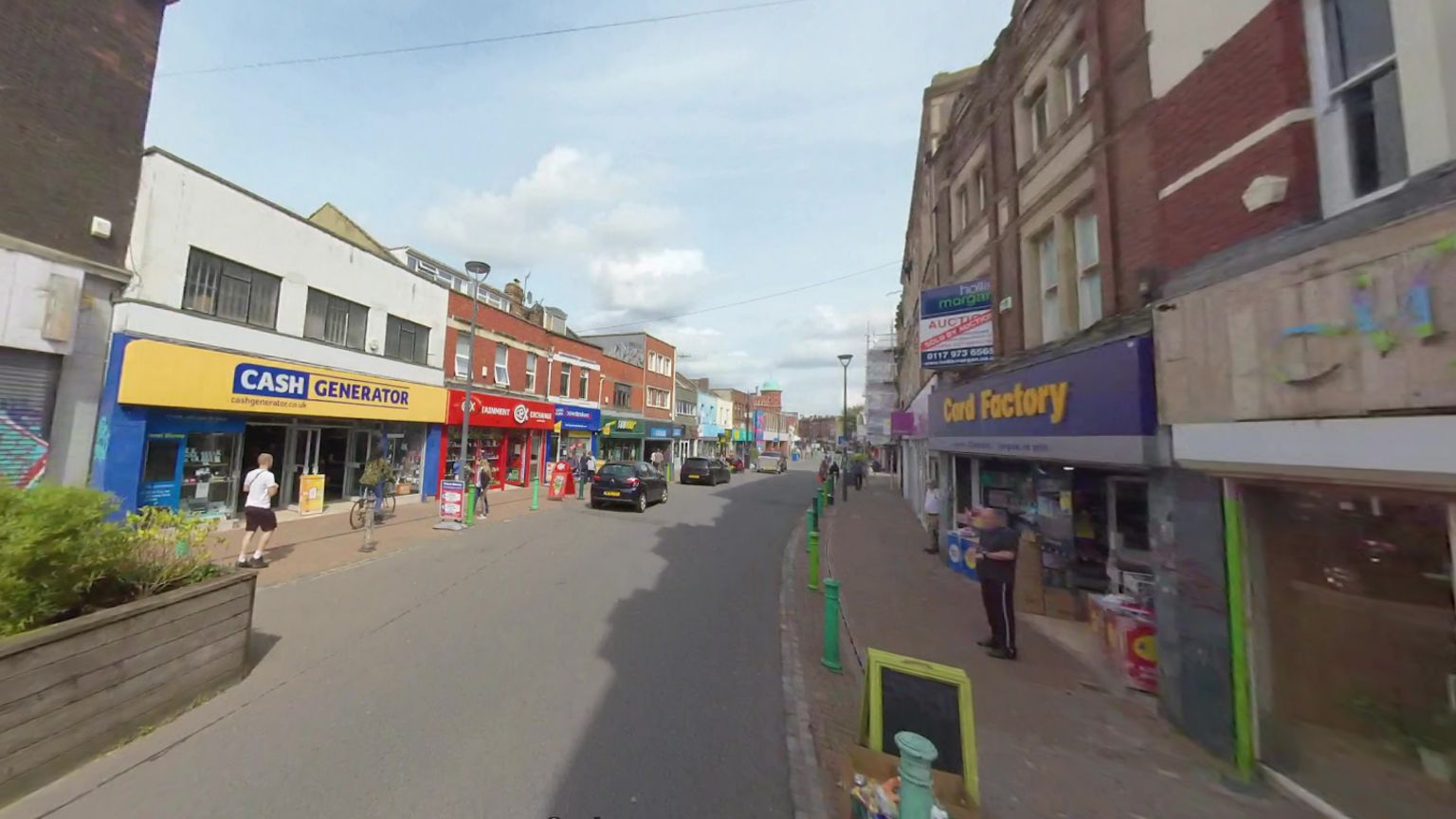 Street scene on East Street in Bedminster, with shops lining both sides, and some parked cars.