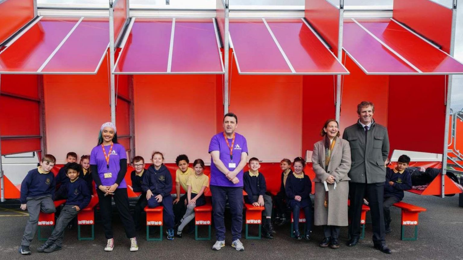 School children sitting outside the mobile art museum