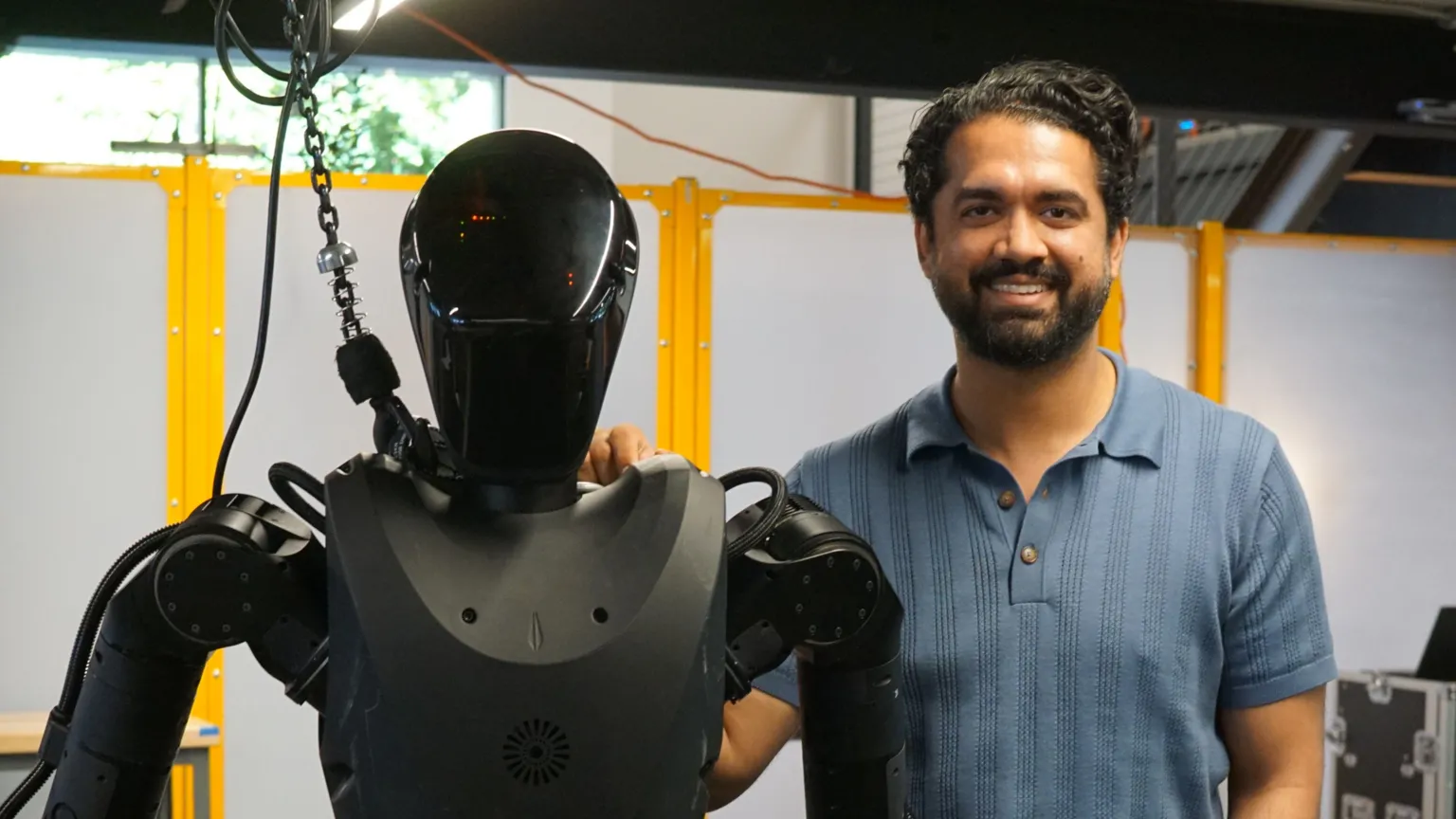 Zoe Corbyn Wearing a blue t-shirt, Sankaet Pathak stands next to the black Phantom robot.