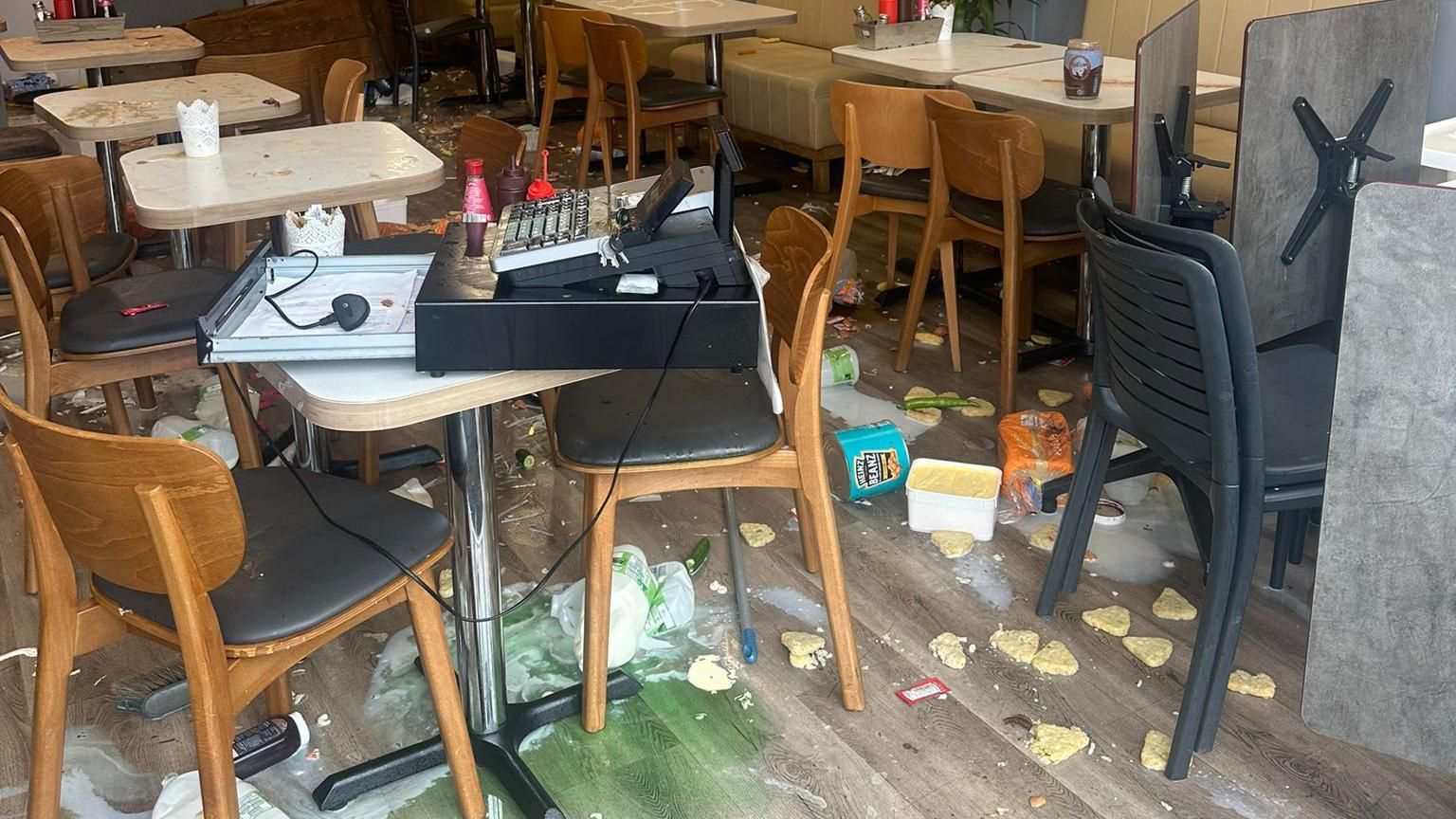 Food, drink and mess on the floor of the cafe, with the till dragged on to a table