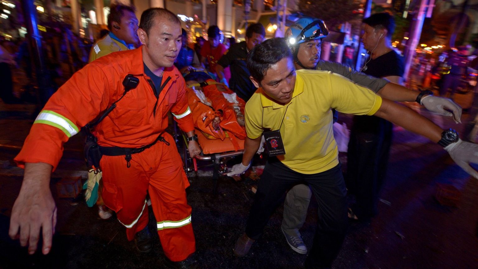 Rescue workers carry an injured person away from a bomb blast in Bangkok